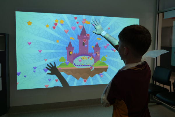 Child with arm in sling waving arm in front of interactive projector in Austin Health Paediatric Emergency Department